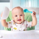 The child holds a plate and spoon. He is happy 